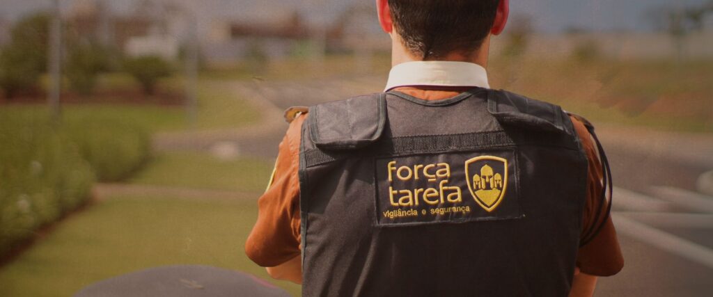 vigilante de empresa de vigilância e segurança residencial de costas vigiando o local